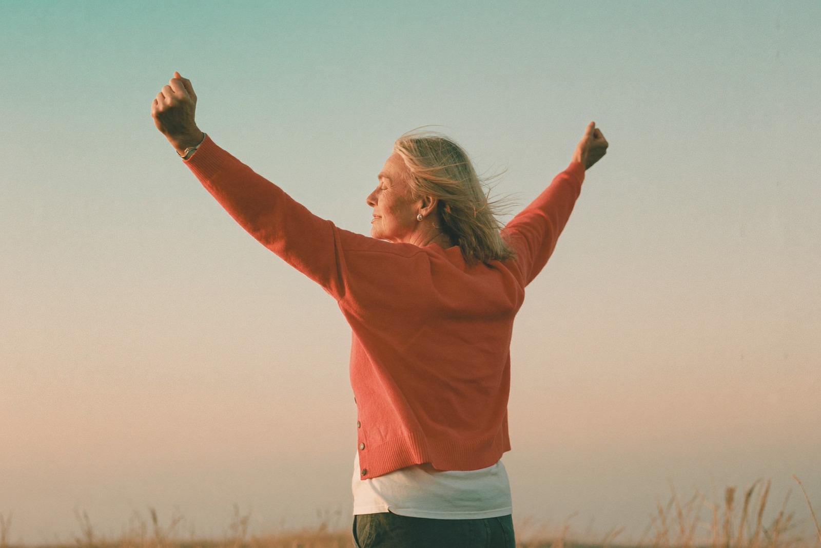 Formation chemin de vie : femme bras ouverts face au lever du soleil en haut d'une colline