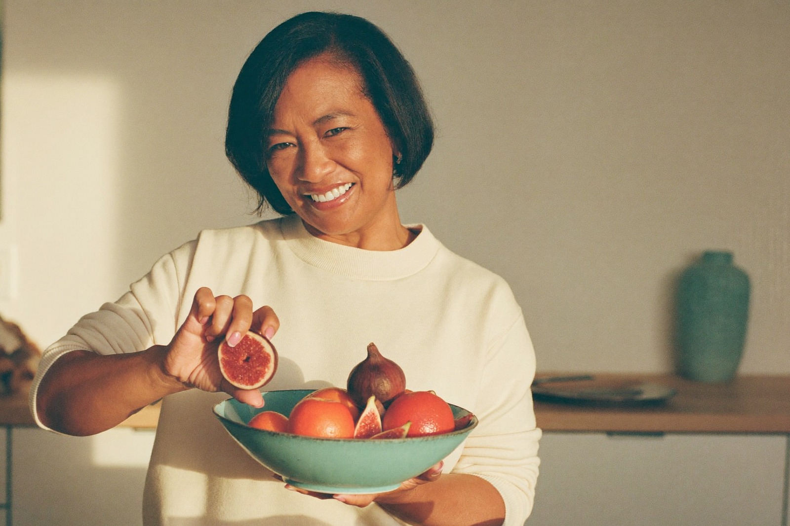 Formation beauté santé et nutrition : femme lumineuse tenant un bol de fruits frais dans une cuisine claire