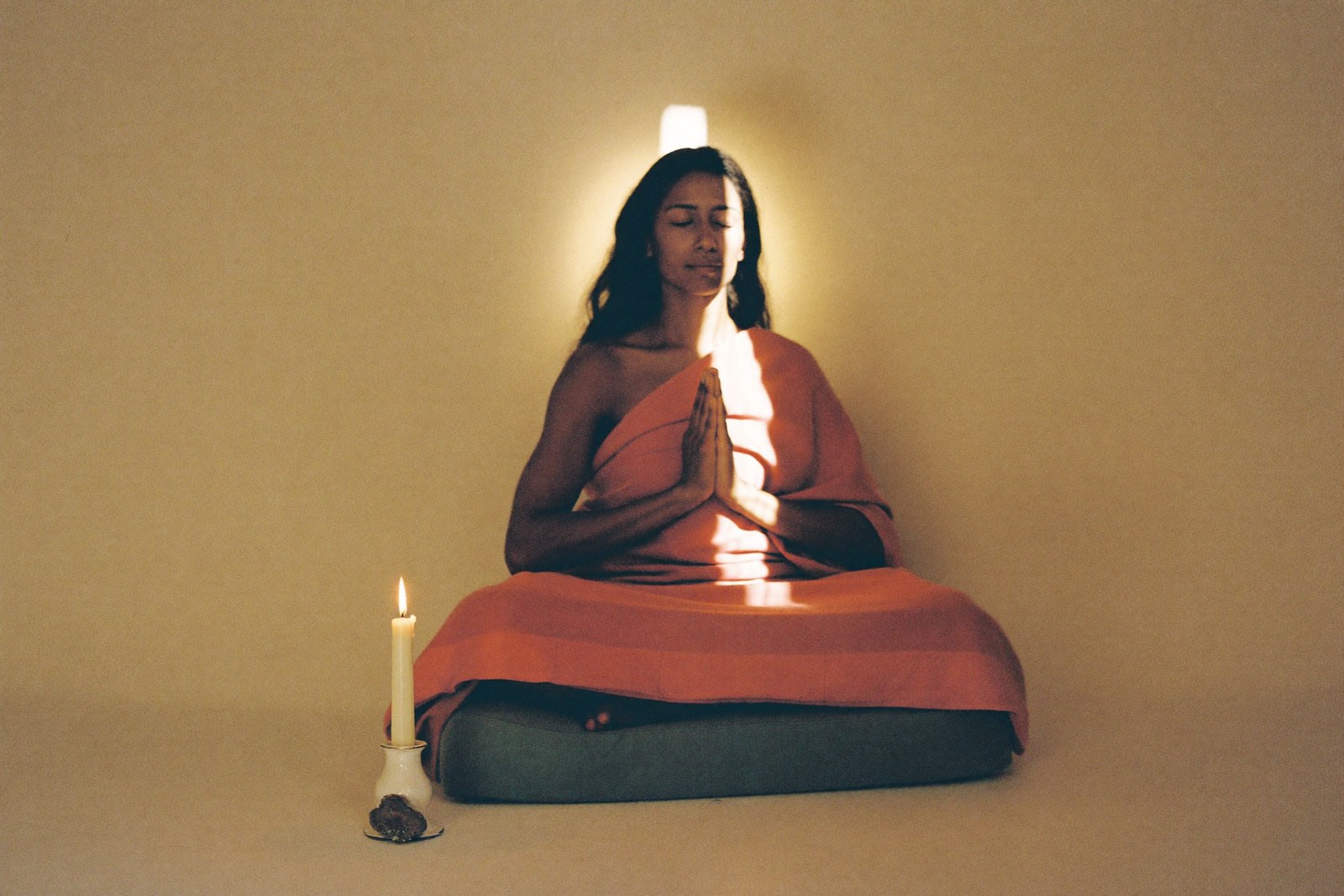 Formation spiritualité : femme en méditation paisible à la lumière d'une bougie, mains près du coeur