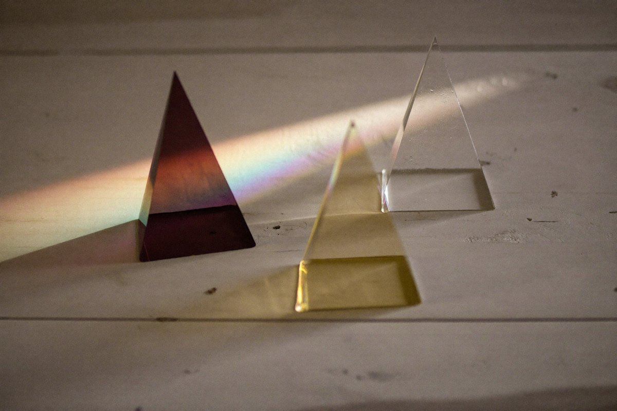 Trois prismes de verre dont les reflets se rejoignent en une seule lumière