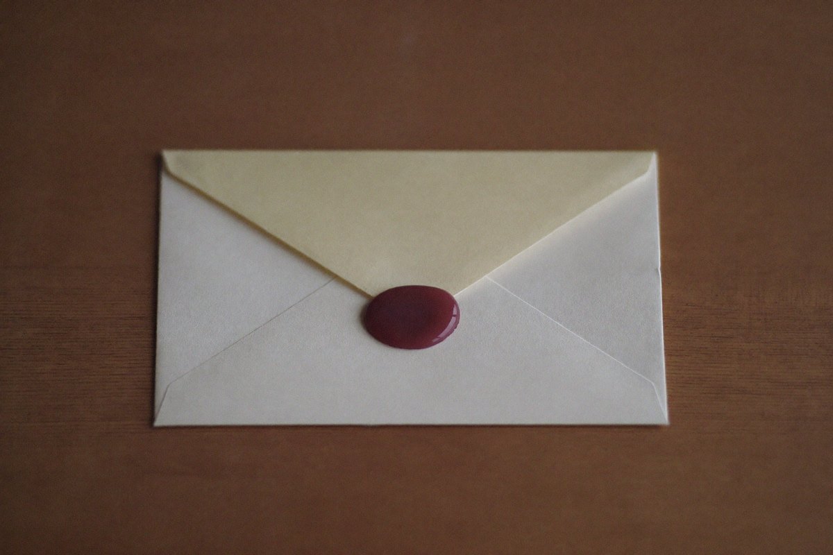 Une enveloppe crème scellée d'un cachet de cire prune